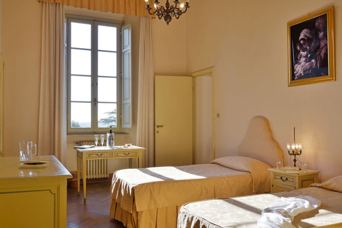 Bright twin bedded room with pale yellow walls and a framed portrait at Midnight Ball