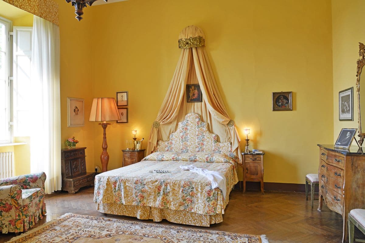 Yellow draped canopy bed with matching upholstered headboard in a period bedroom at Midnight Ball
