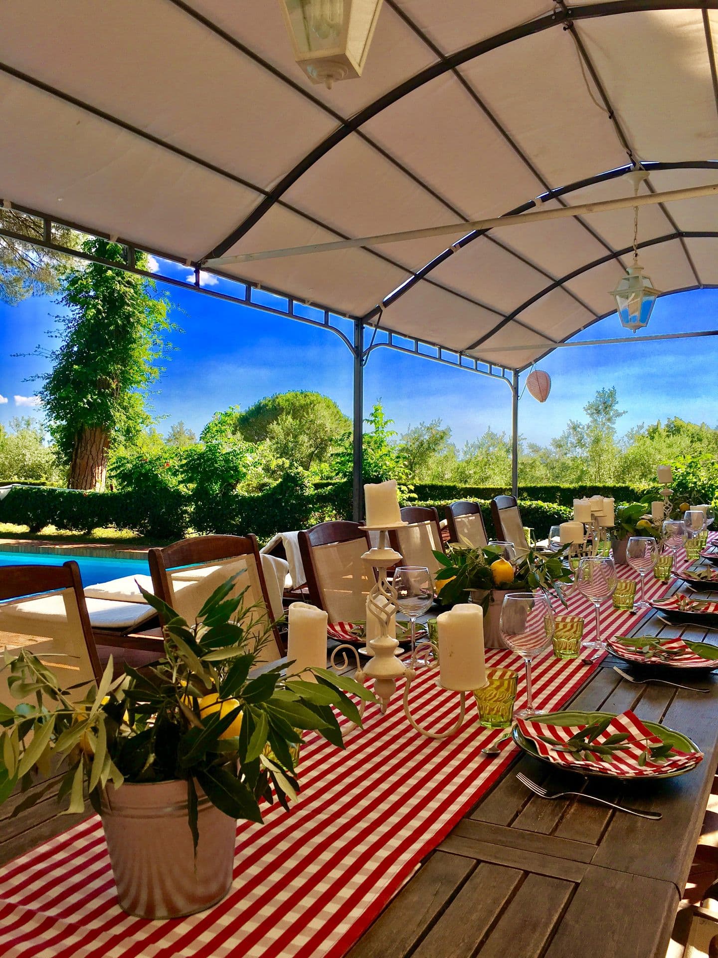 Long table laid with a red and white checked cloth on a covered poolside terrace at Midnight Ball