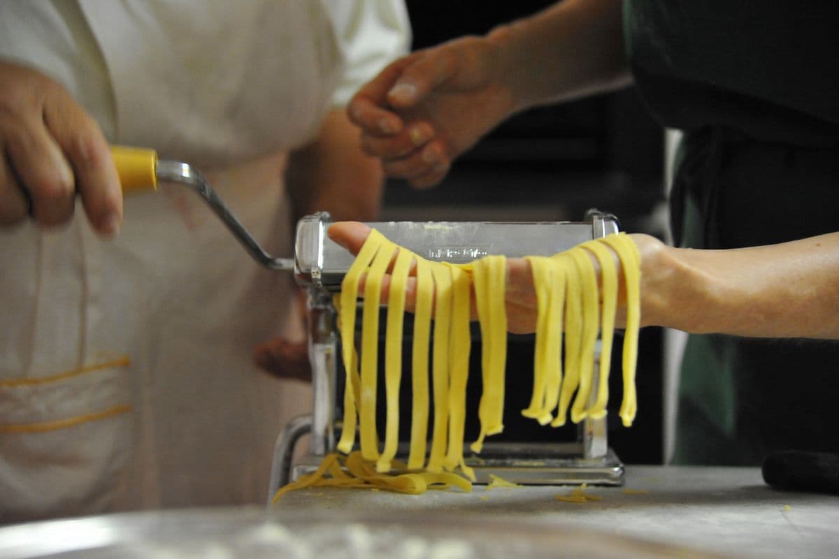 Fresh pasta being rolled through a traditional machine as part of a private cookery experience at Midnight Ball