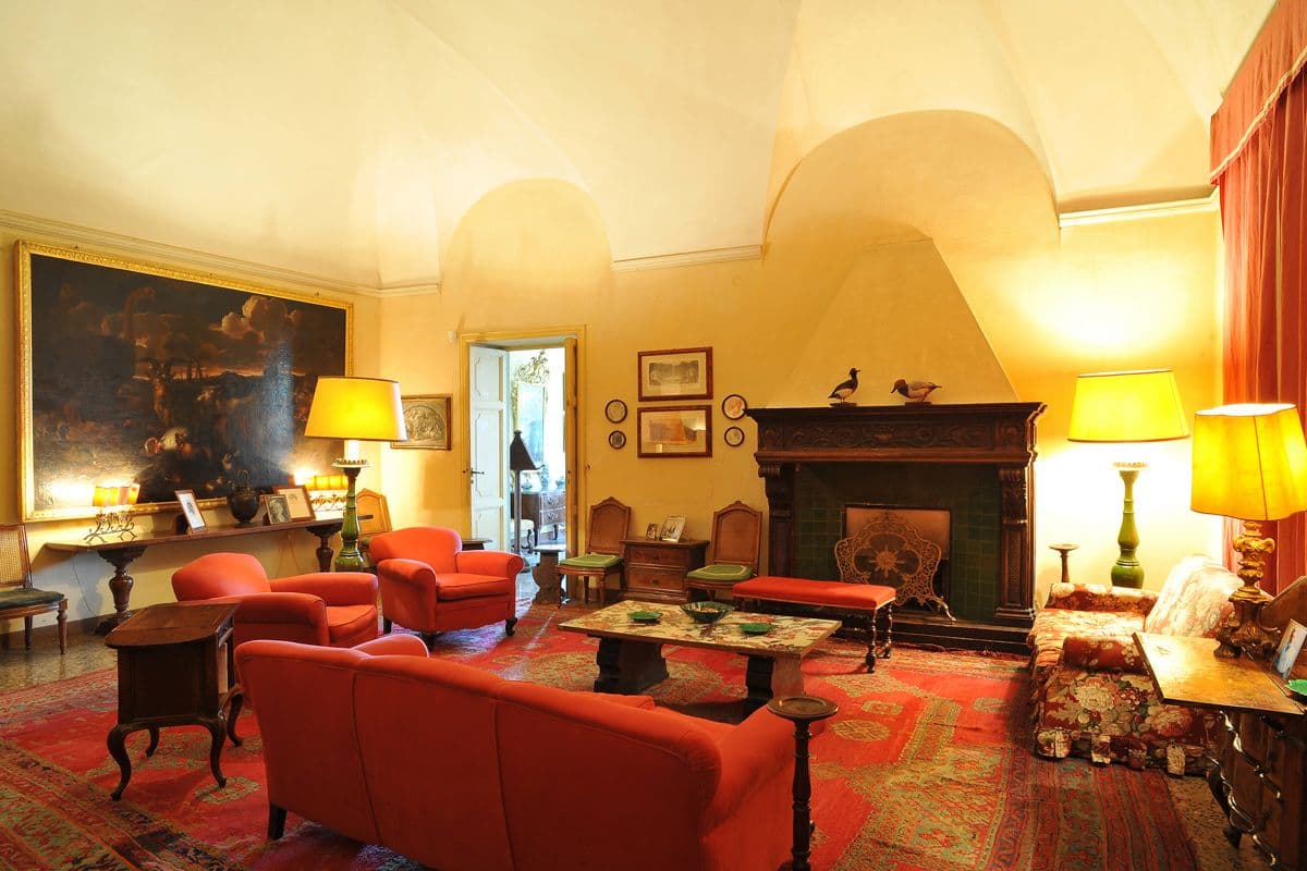 Red upholstered armchairs and a stone fireplace in a frescoed sitting room at Midnight Ball