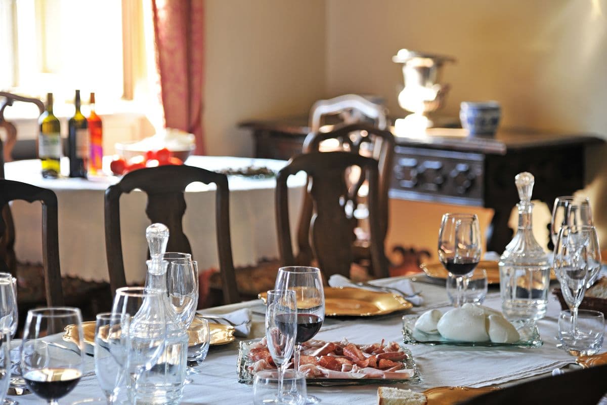 Antique sideboard with wine bottles and glasses set beside a dining table at Midnight Ball