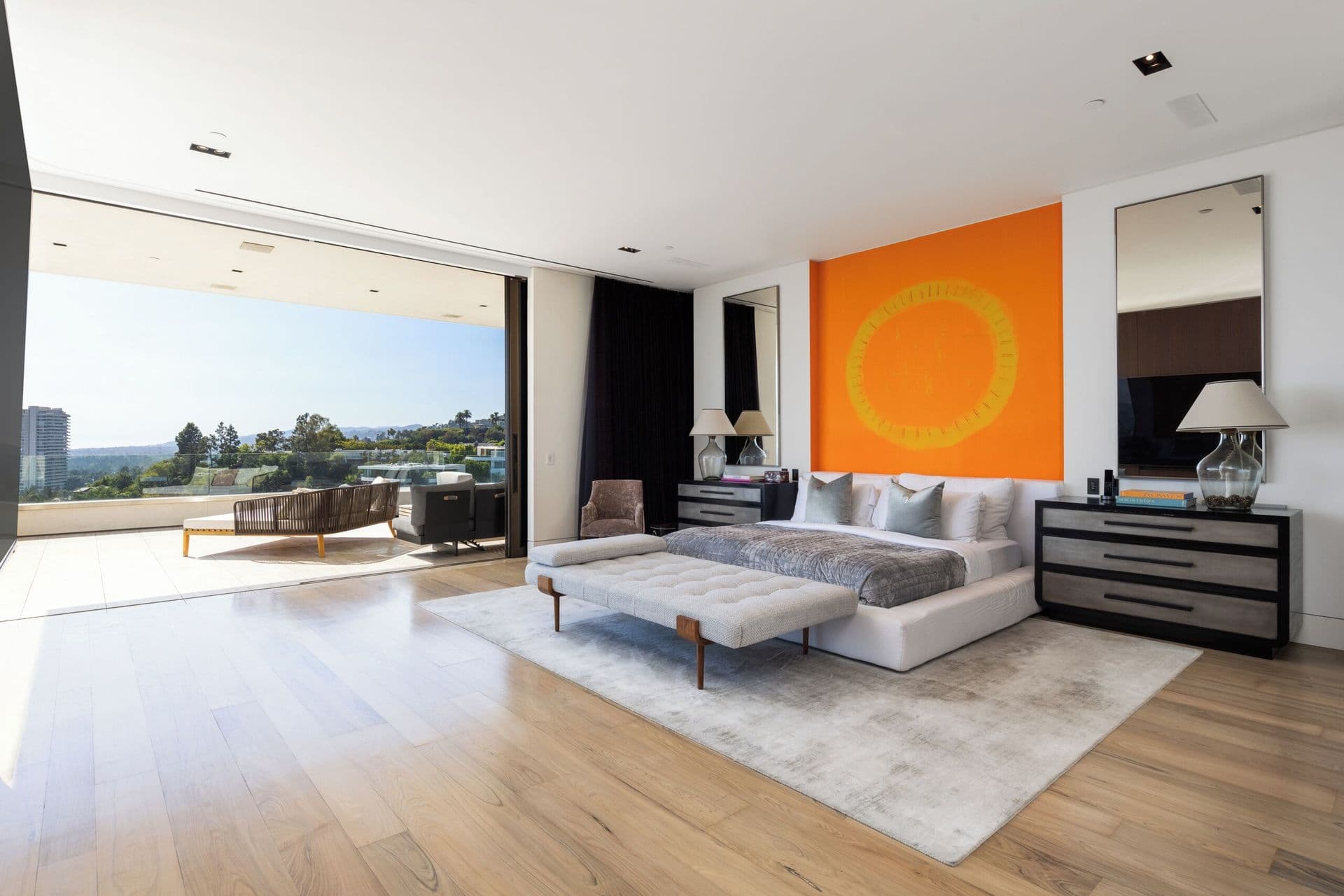 Bright bedroom with a white daybed, orange artwork and floor-to-ceiling windows