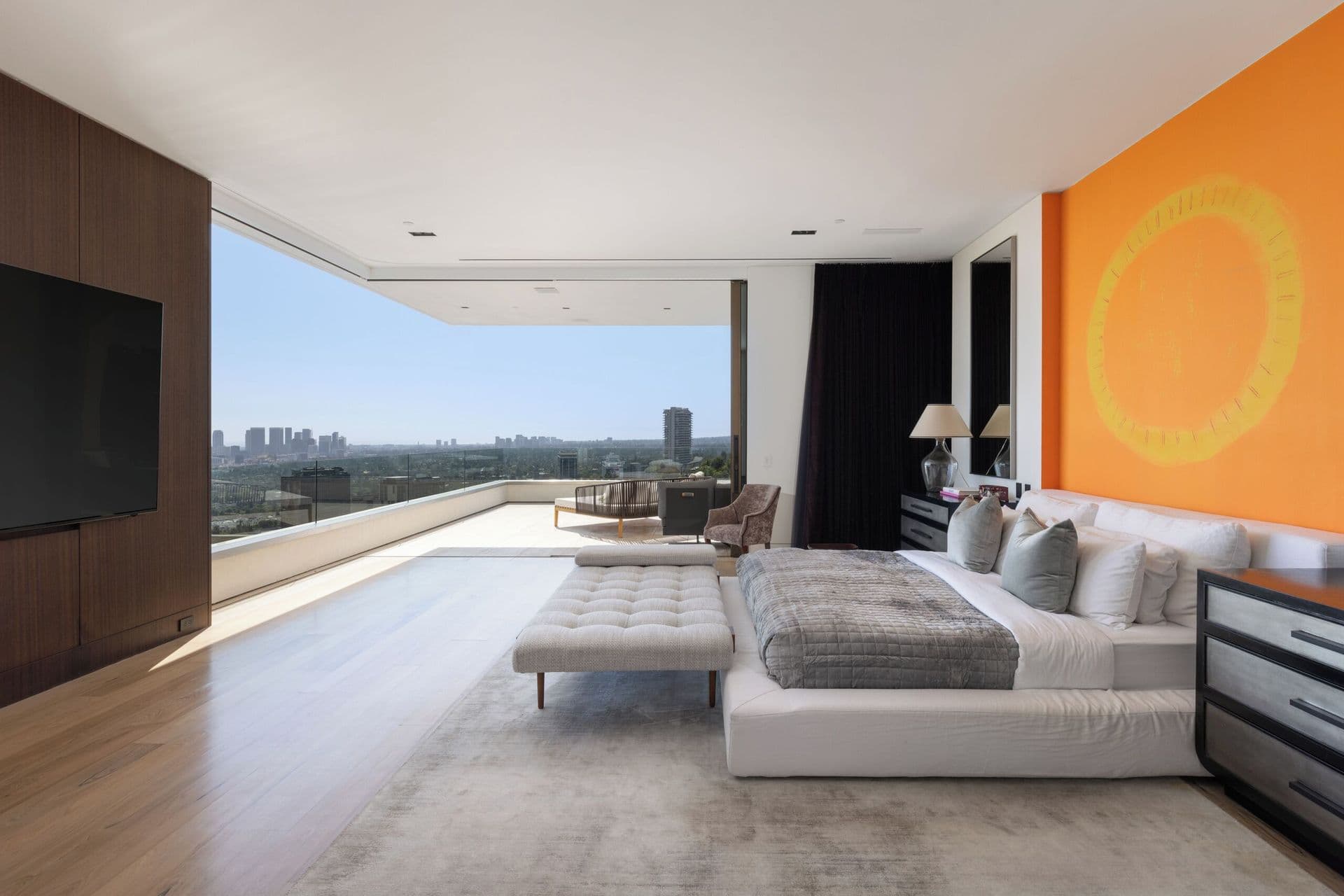 Bedroom with a bold orange artwork, television and private terrace with city views