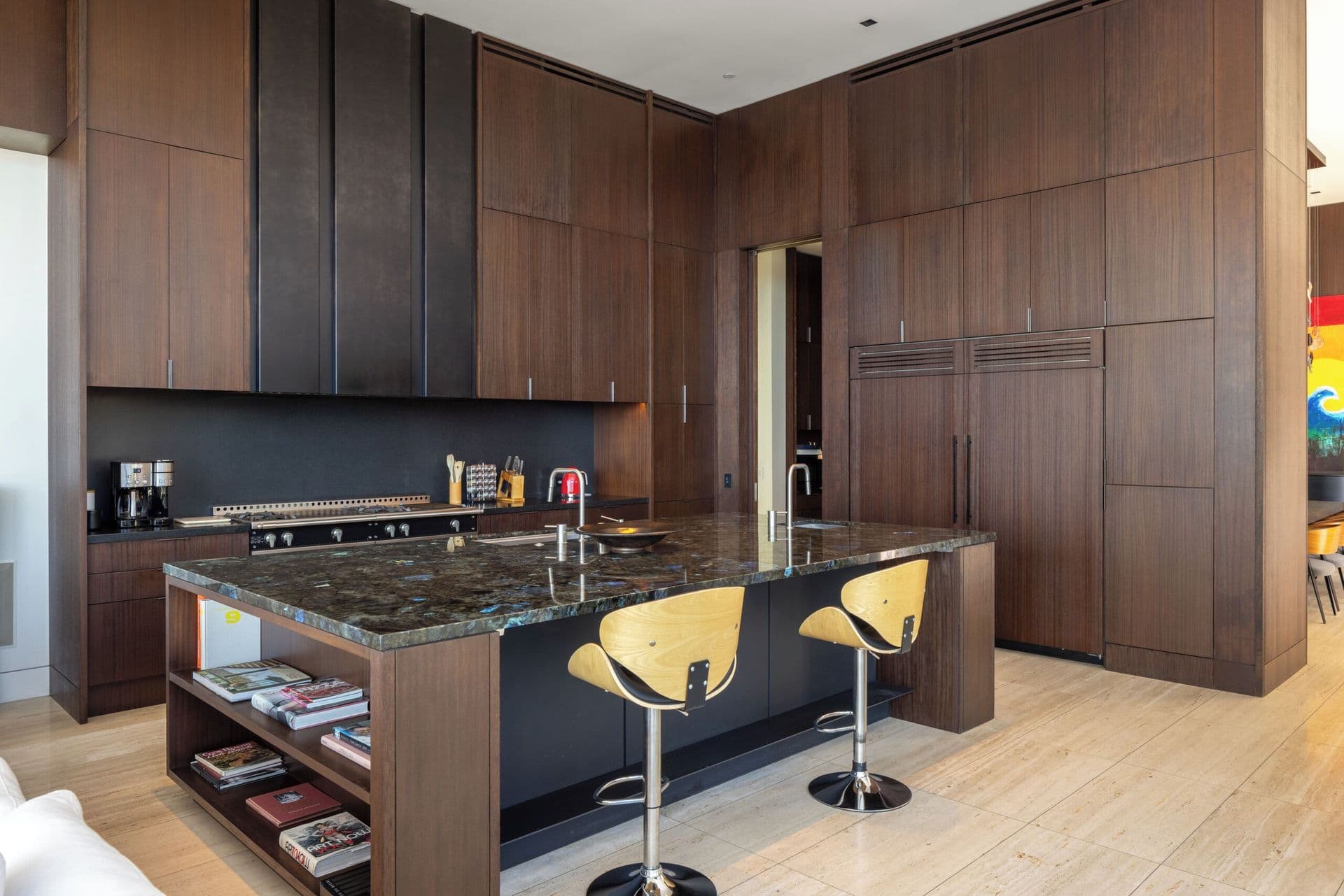 Dark stone kitchen island with bar stool seating and built-in cabinetry