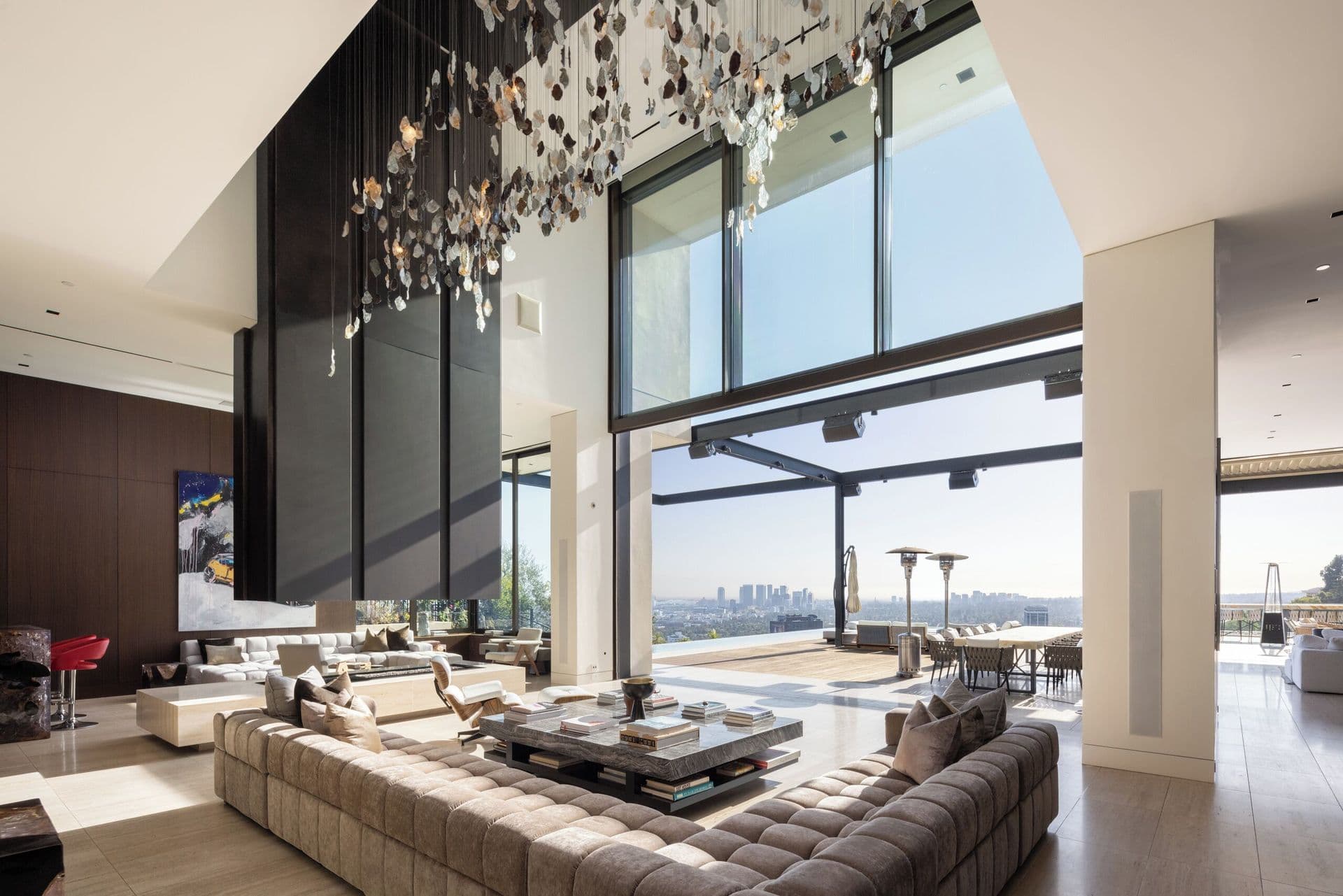 Double-height living room with a statement chandelier and floor-to-ceiling glass onto the city view