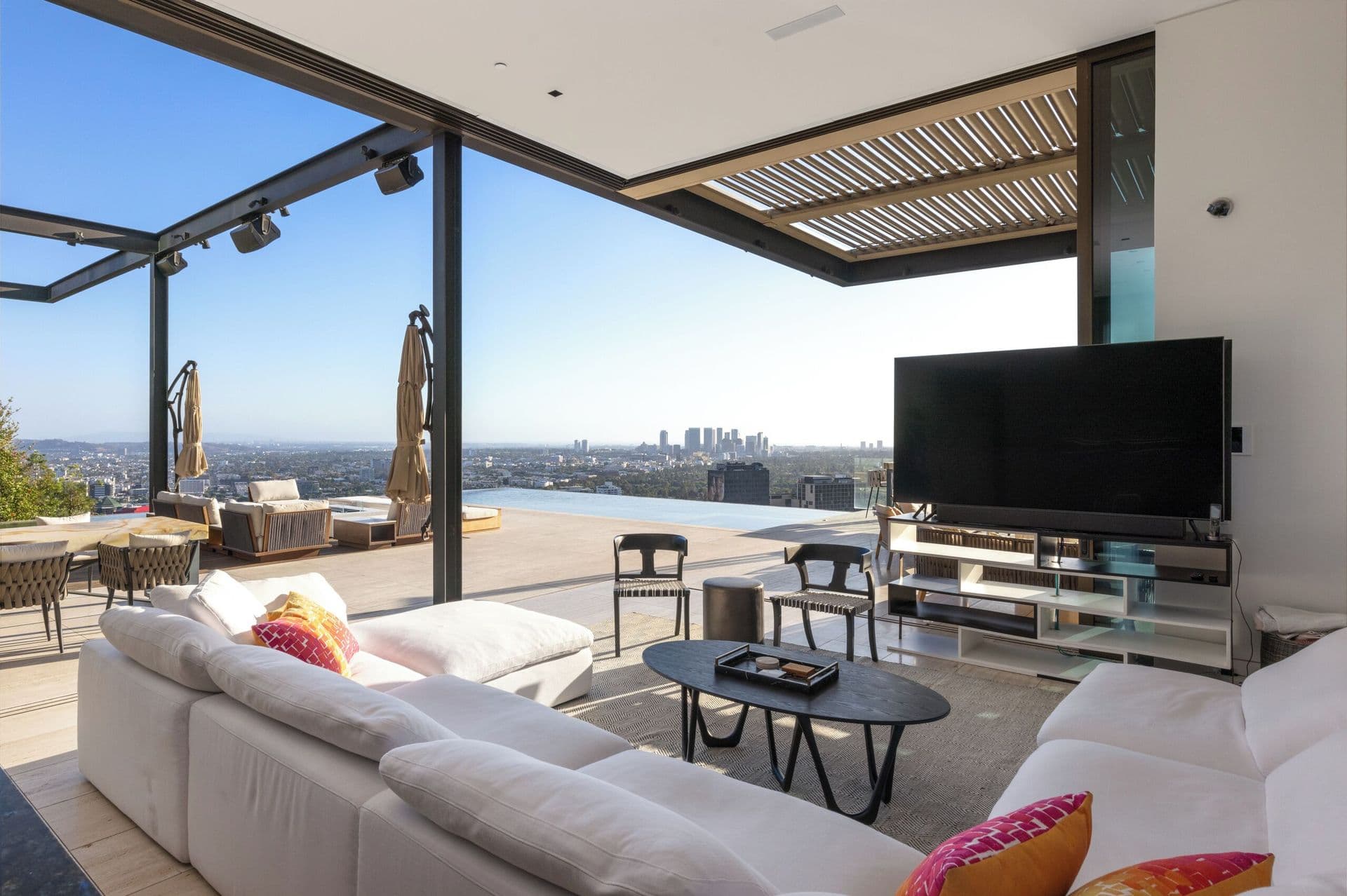 Covered outdoor terrace with lounge seating and retractable pergola overlooking the city