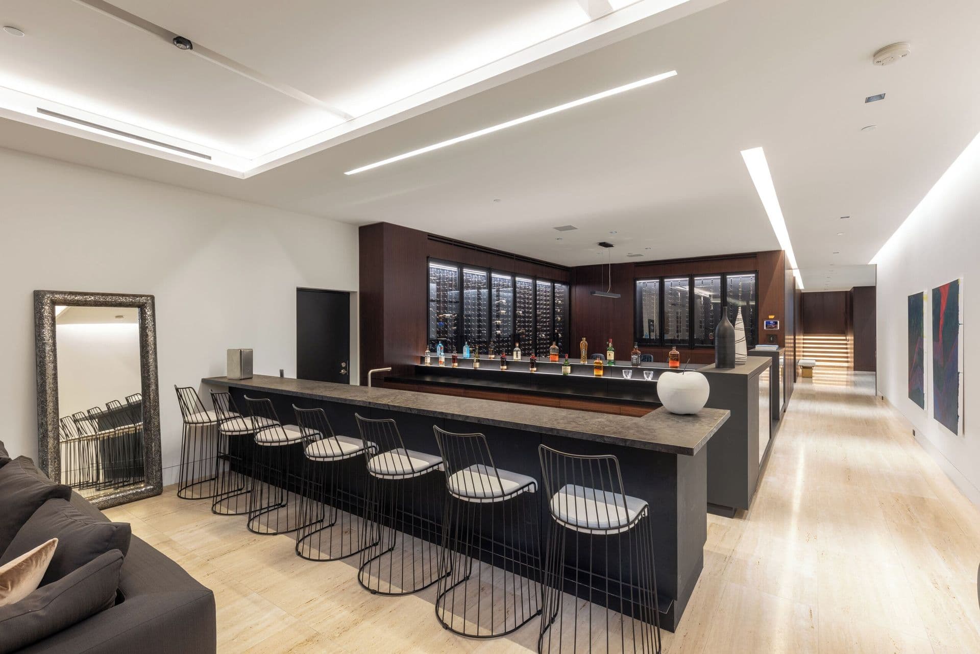 Home bar with a long counter and glass-enclosed wine display wall