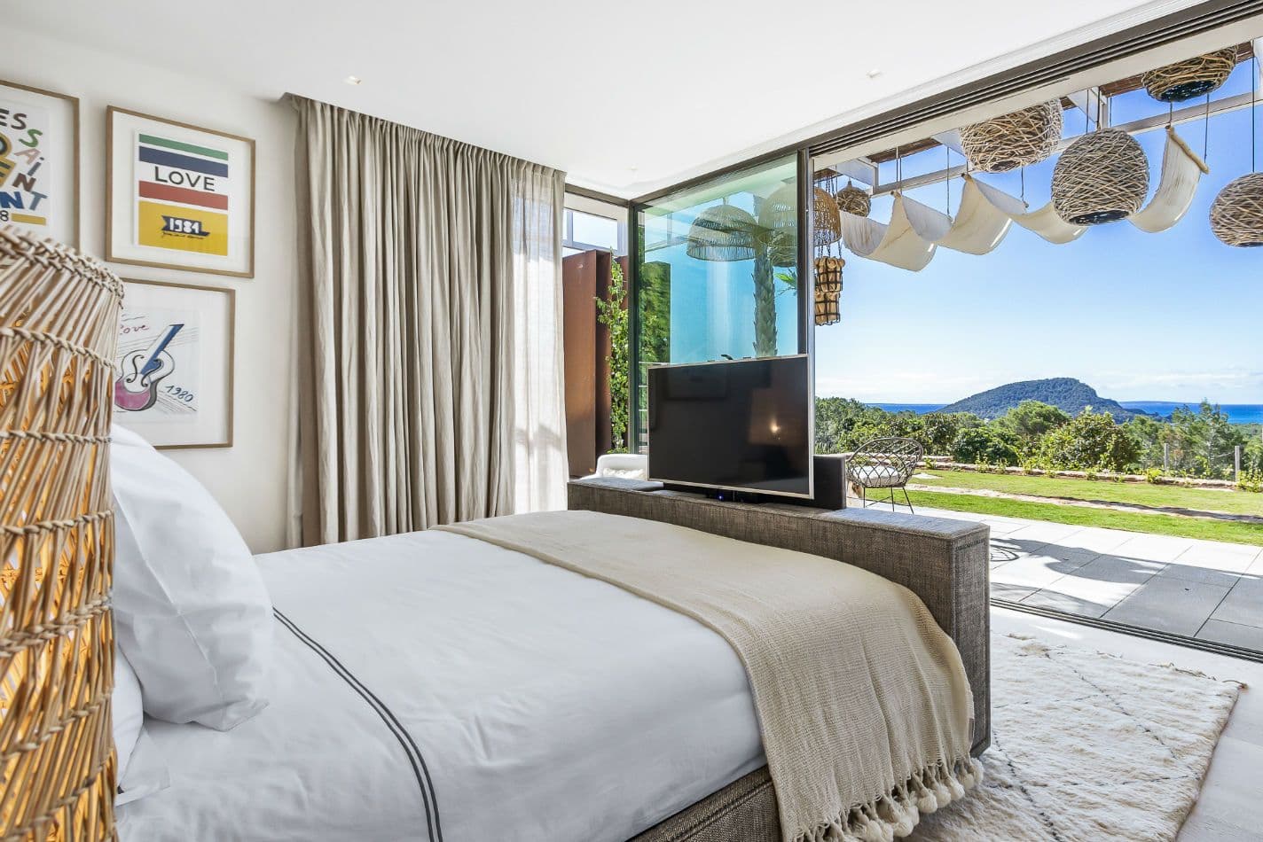 Double bedroom with a television and sea view through sliding doors at Aphrodite's Oasis, Ibiza