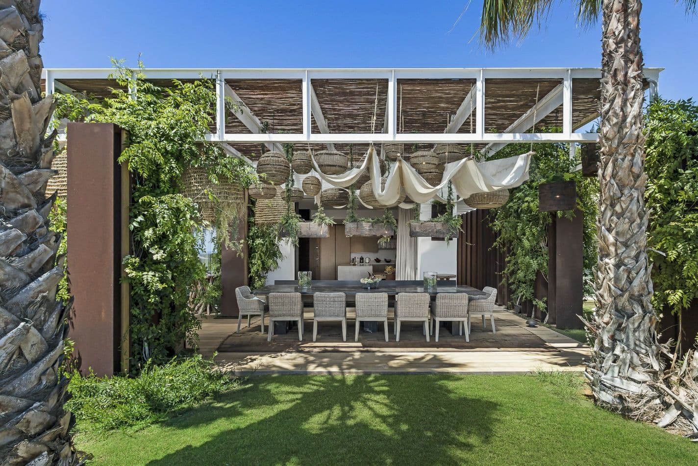 Outdoor dining under a draped pergola between palms at Aphrodite's Oasis, Ibiza