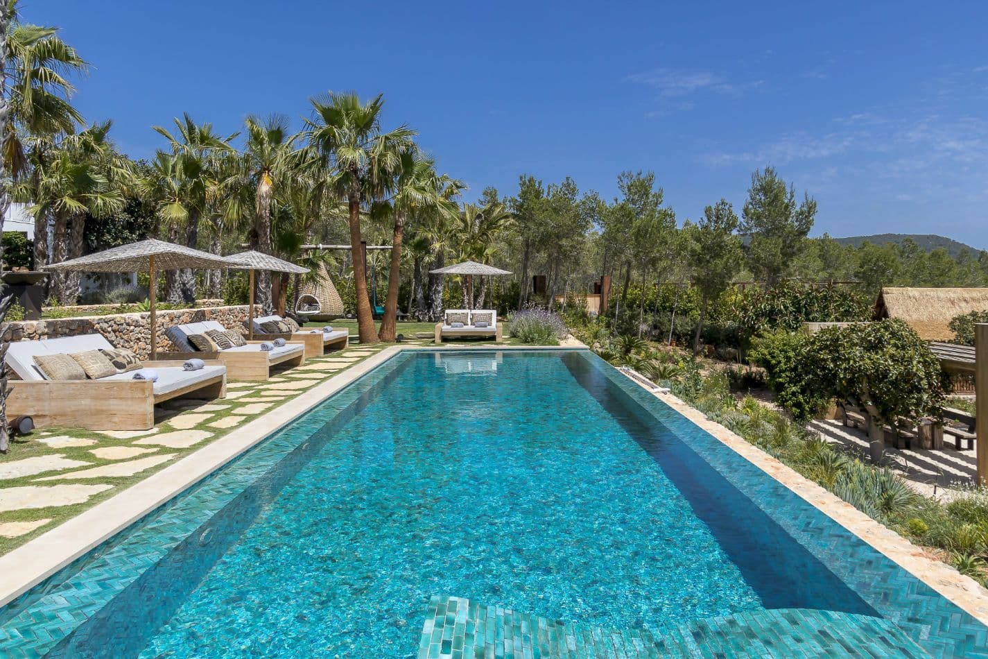 Long swimming pool lined with palms and day beds at Aphrodite's Oasis, Ibiza