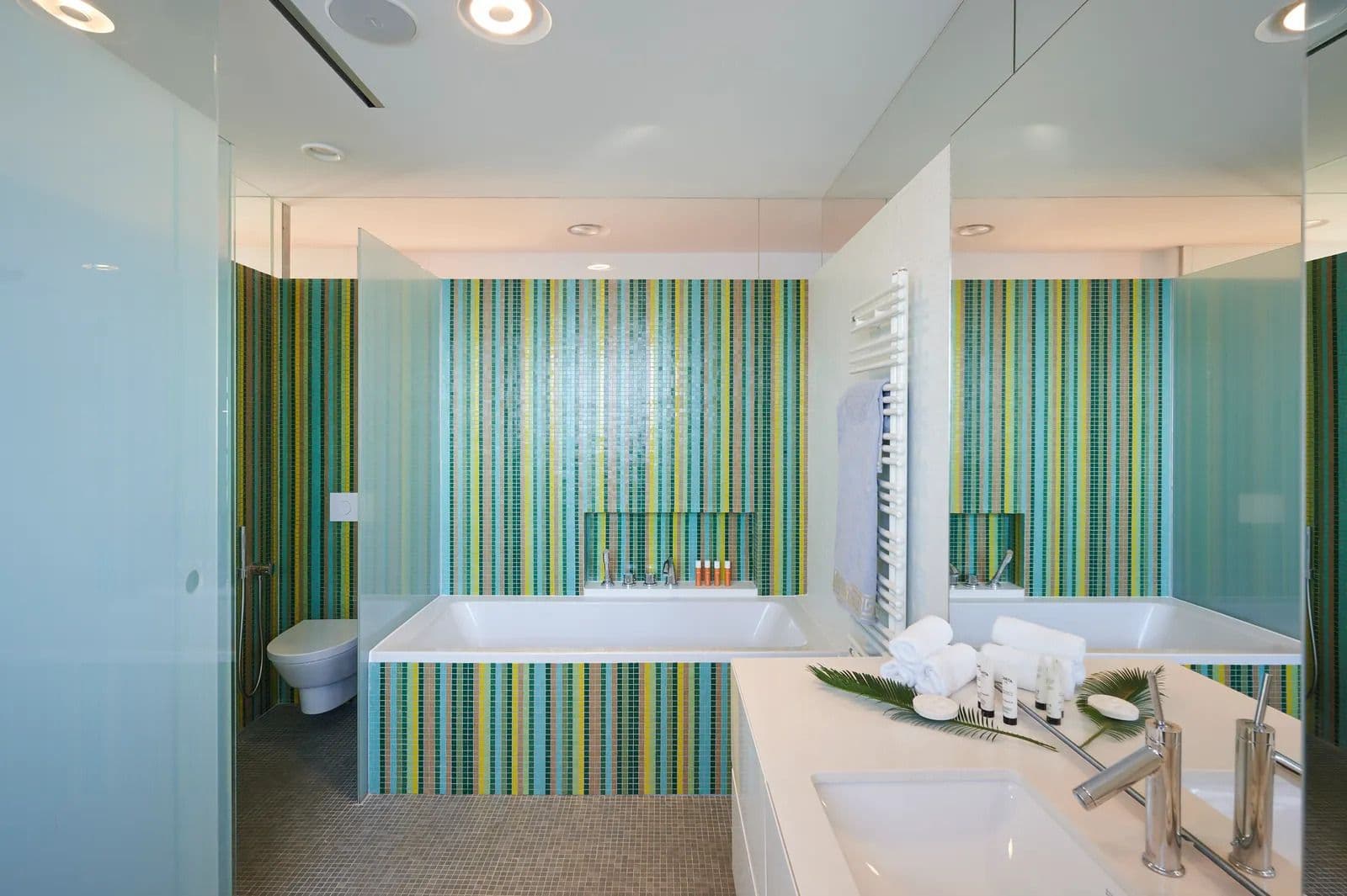 Ensuite bathroom with green and white striped tiling, a freestanding tub and a double vanity.