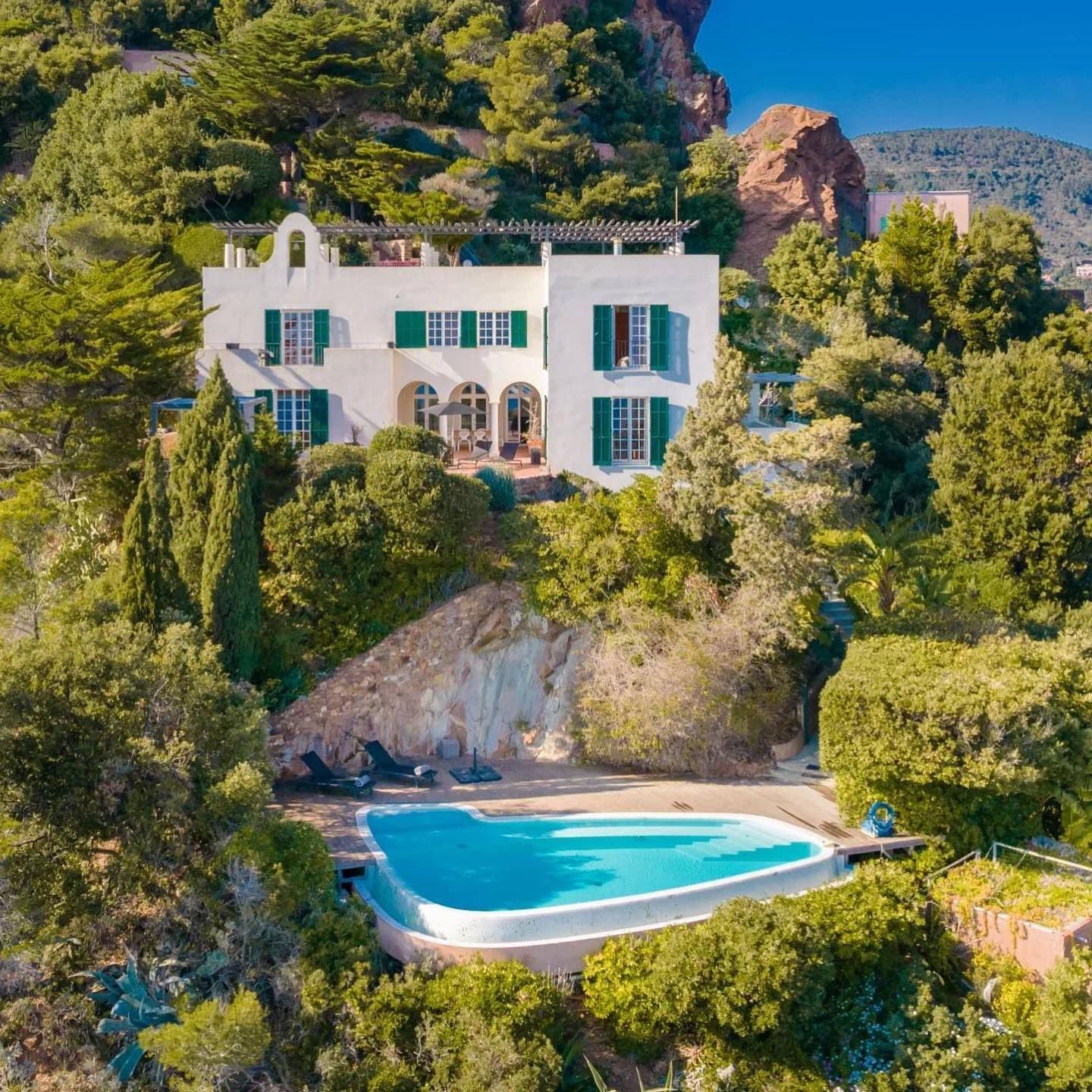 Aerial view of the villa and pool nestled among pine trees on the headland.