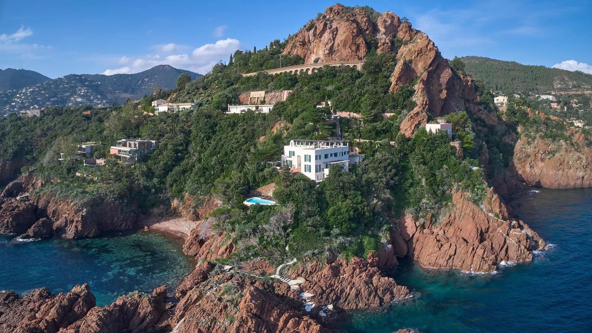 Wide aerial view showing the villa's position on the red rock cliffs of the Esterel coastline.