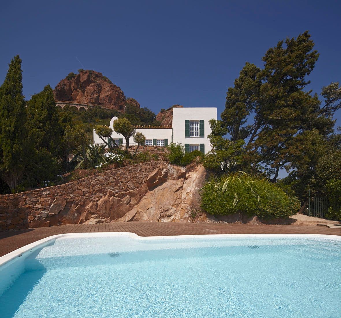 Close view of the curved swimming pool set against natural rock outcrops and pine trees.