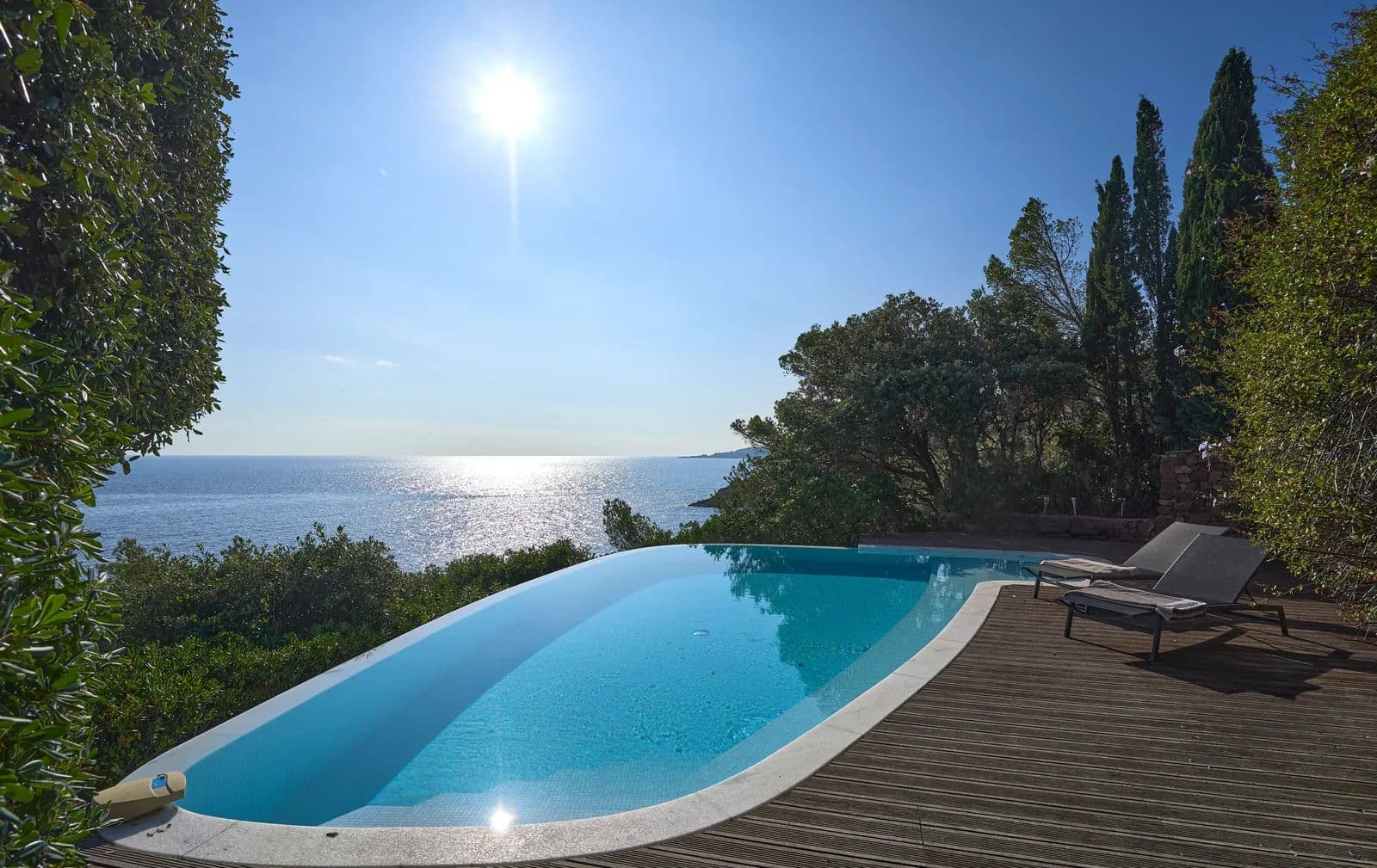 Infinity pool and wooden deck at dusk with uninterrupted sea views.