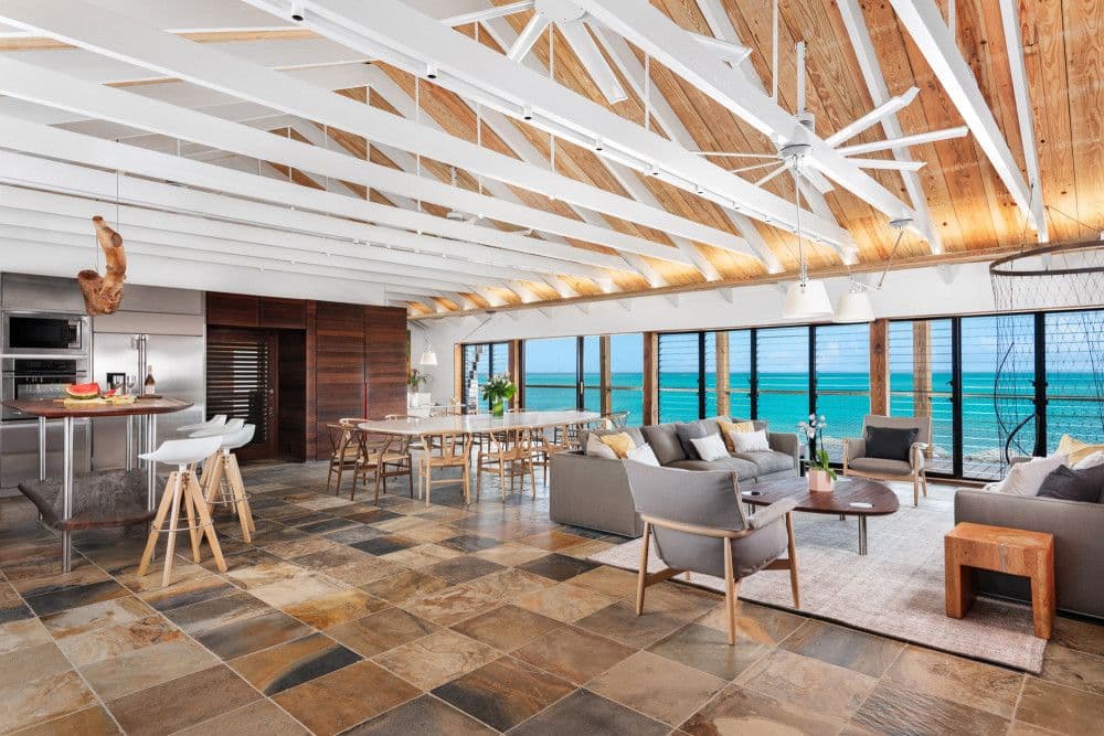 Open-plan living, dining and kitchen under a vaulted beamed ceiling with ocean views