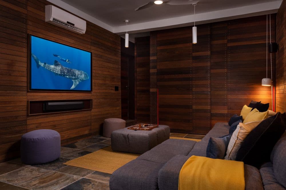Timber-panelled media room with a large screen and sectional sofa at Silver Sands
