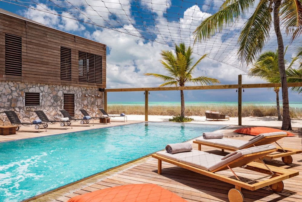 Poolside loungers on a timber deck with the turquoise ocean beyond at Silver Sands