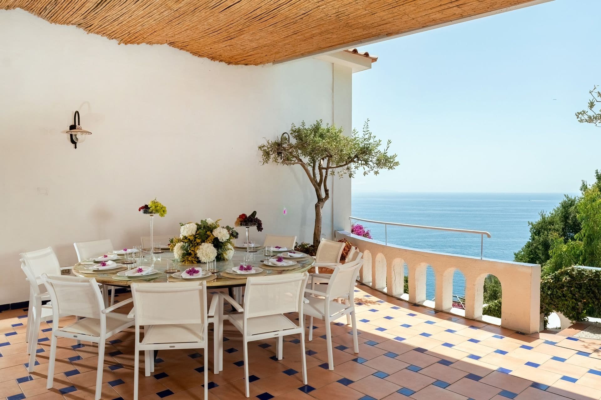 Open-air dining table set for guests on a balustraded terrace at Graceful Sea