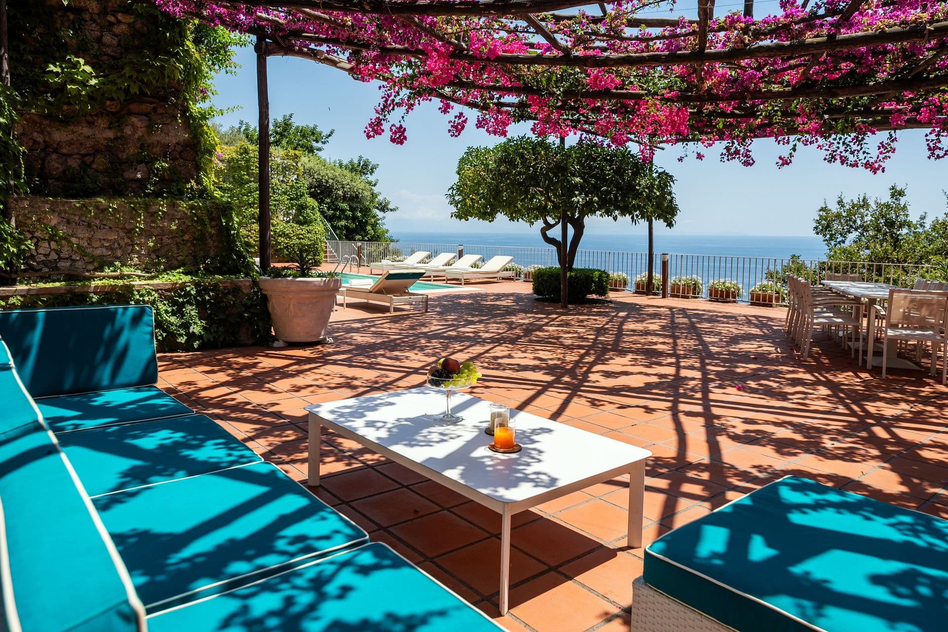 Turquoise sunbeds on a shaded terrace beneath flowering bougainvillea at Graceful Sea