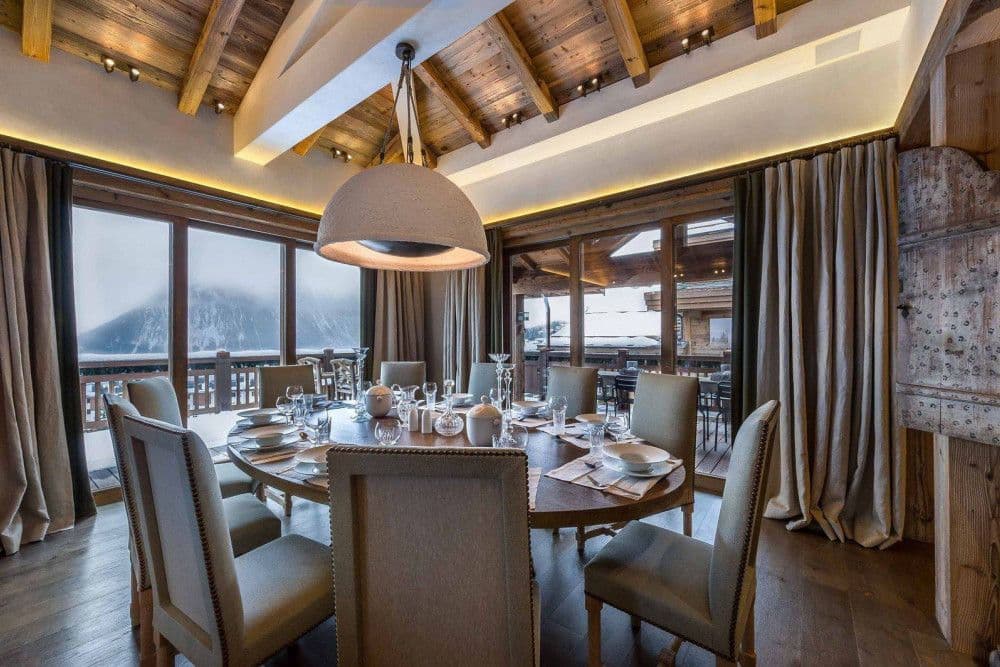 Dining room with mountain views through full-height windows at Courchevel 16