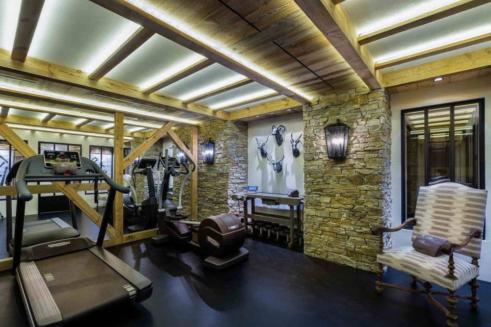 Gym with cardio equipment and stone walls at Courchevel 16