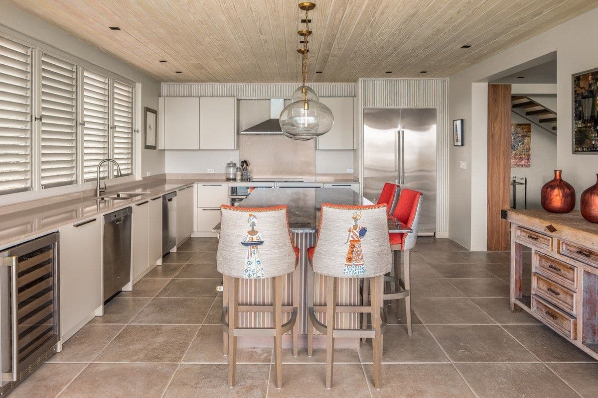 White kitchen with island, breakfast stools and wine fridge at Sea Breeze Cove