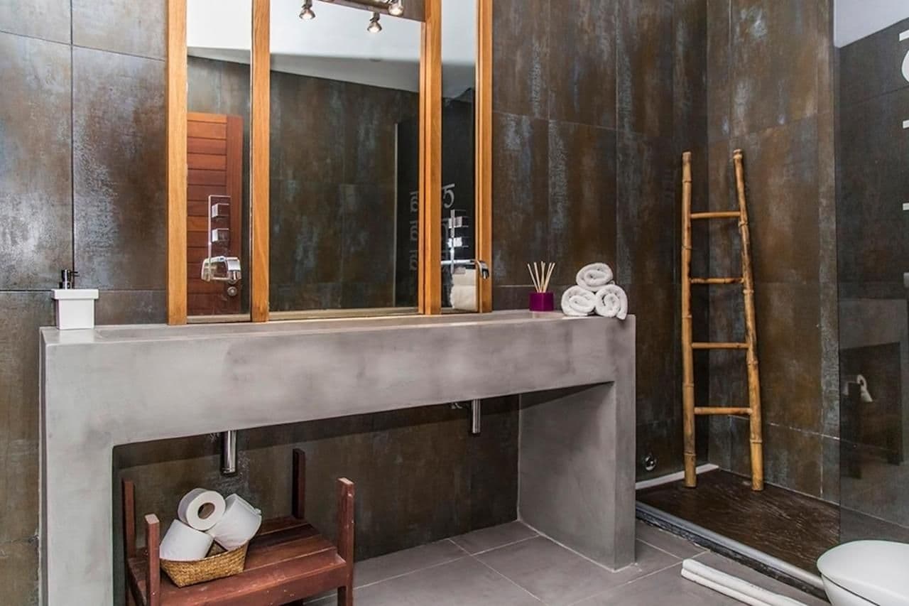Bathroom with a concrete vanity and dark tiling