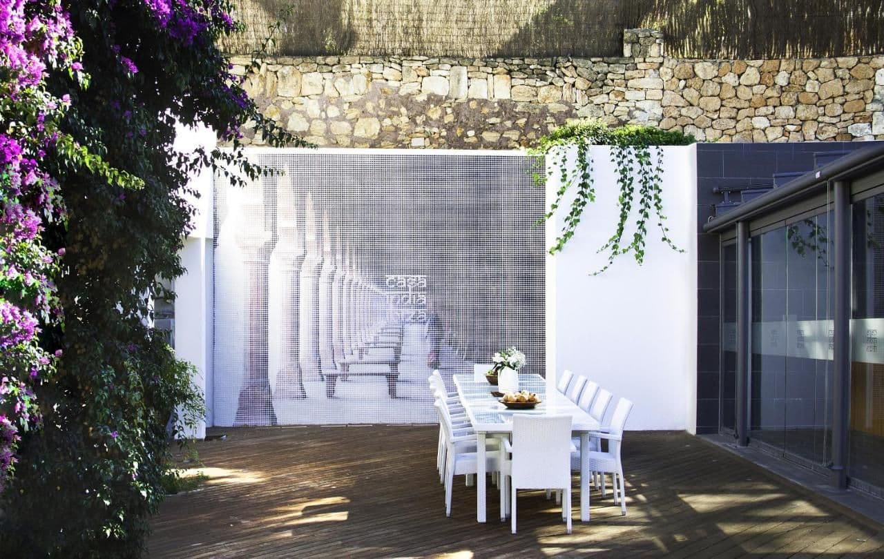 Covered dining terrace with a trompe l'oeil mural and bougainvillea