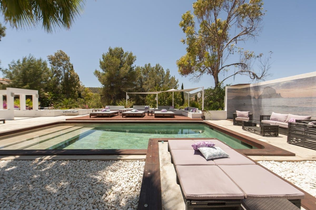 Pool bordered by gravel with built in daybeds and purple cushions