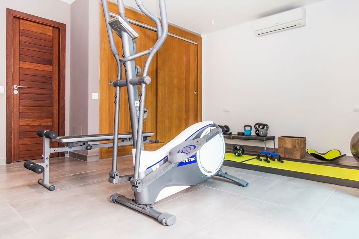 Home gym with an elliptical trainer, weights and yoga mat