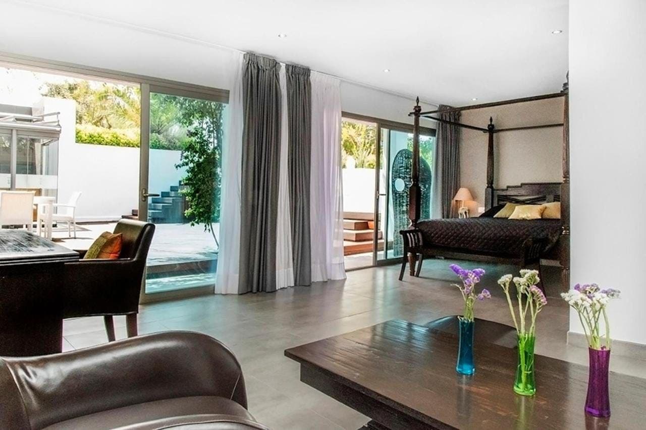 Suite lounge area with a dark four poster bed and glass doors to the pool