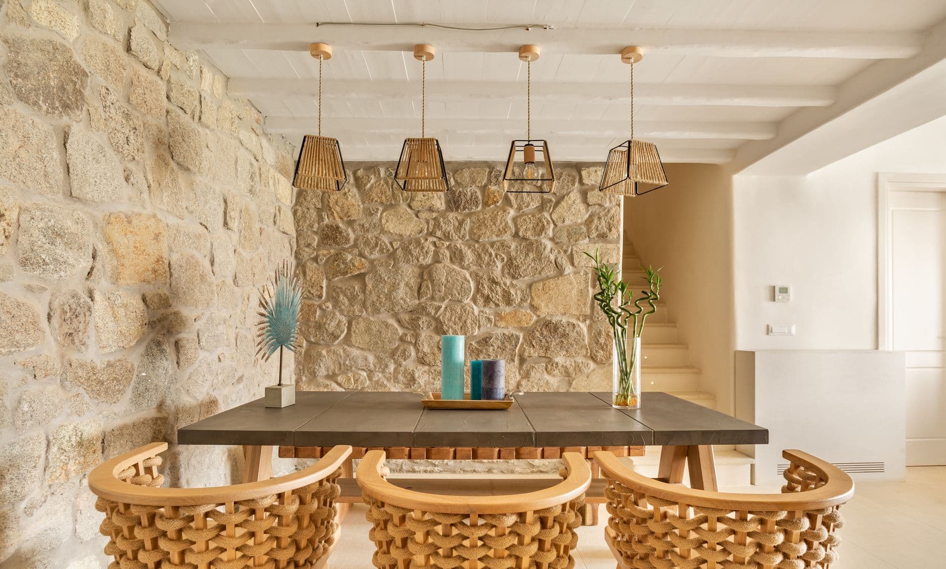 Dining room with rattan chairs beneath a row of pendant lights