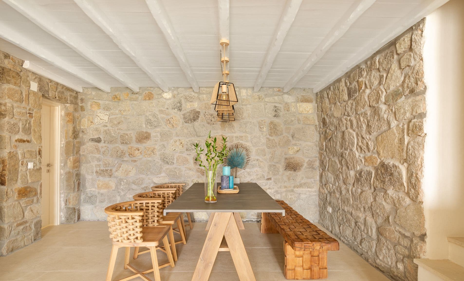 Dining room with wooden table, bench seating and exposed stone wall