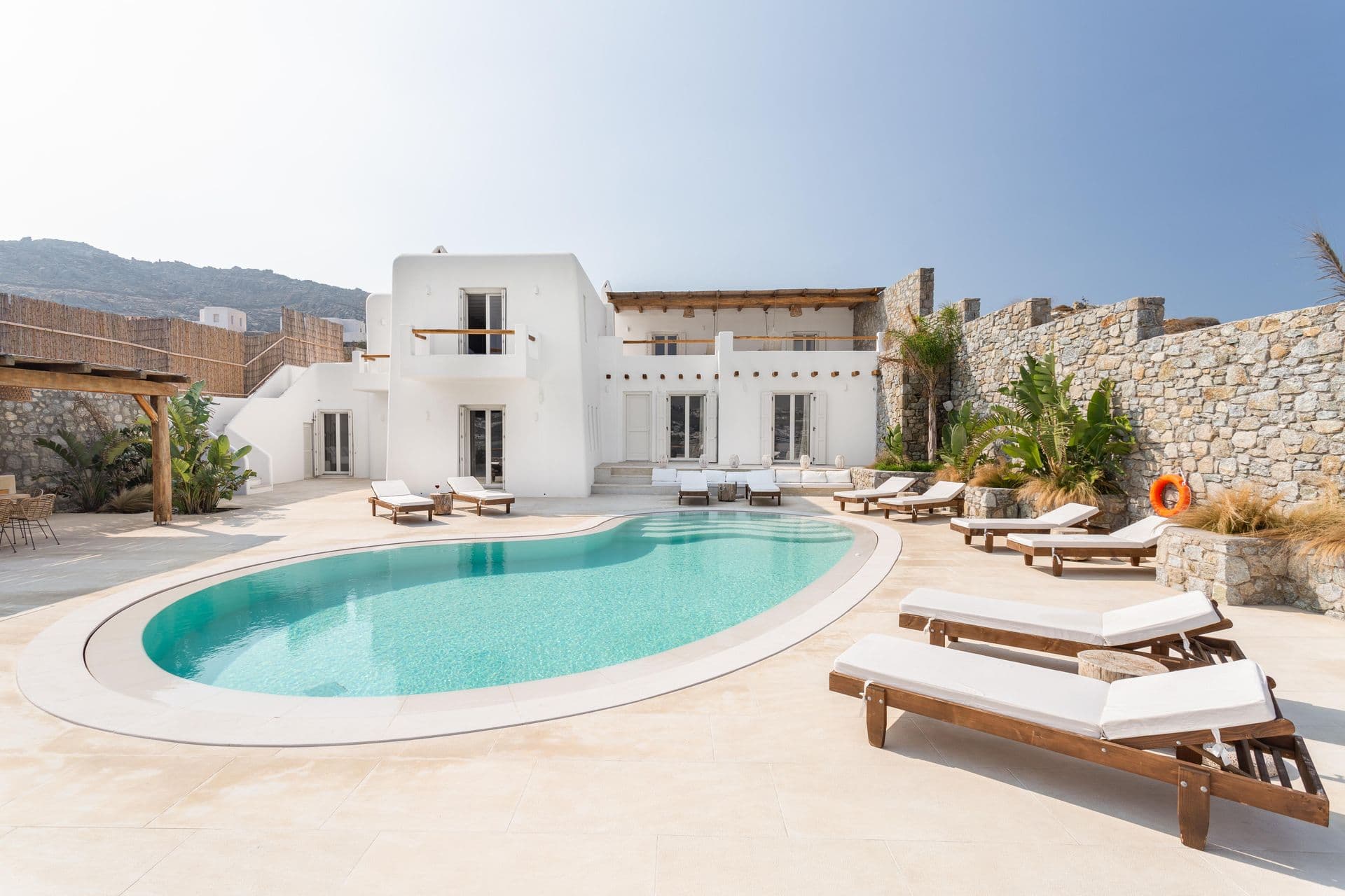 Whitewashed Mykonos villa with curved swimming pool, sun loungers and sea view