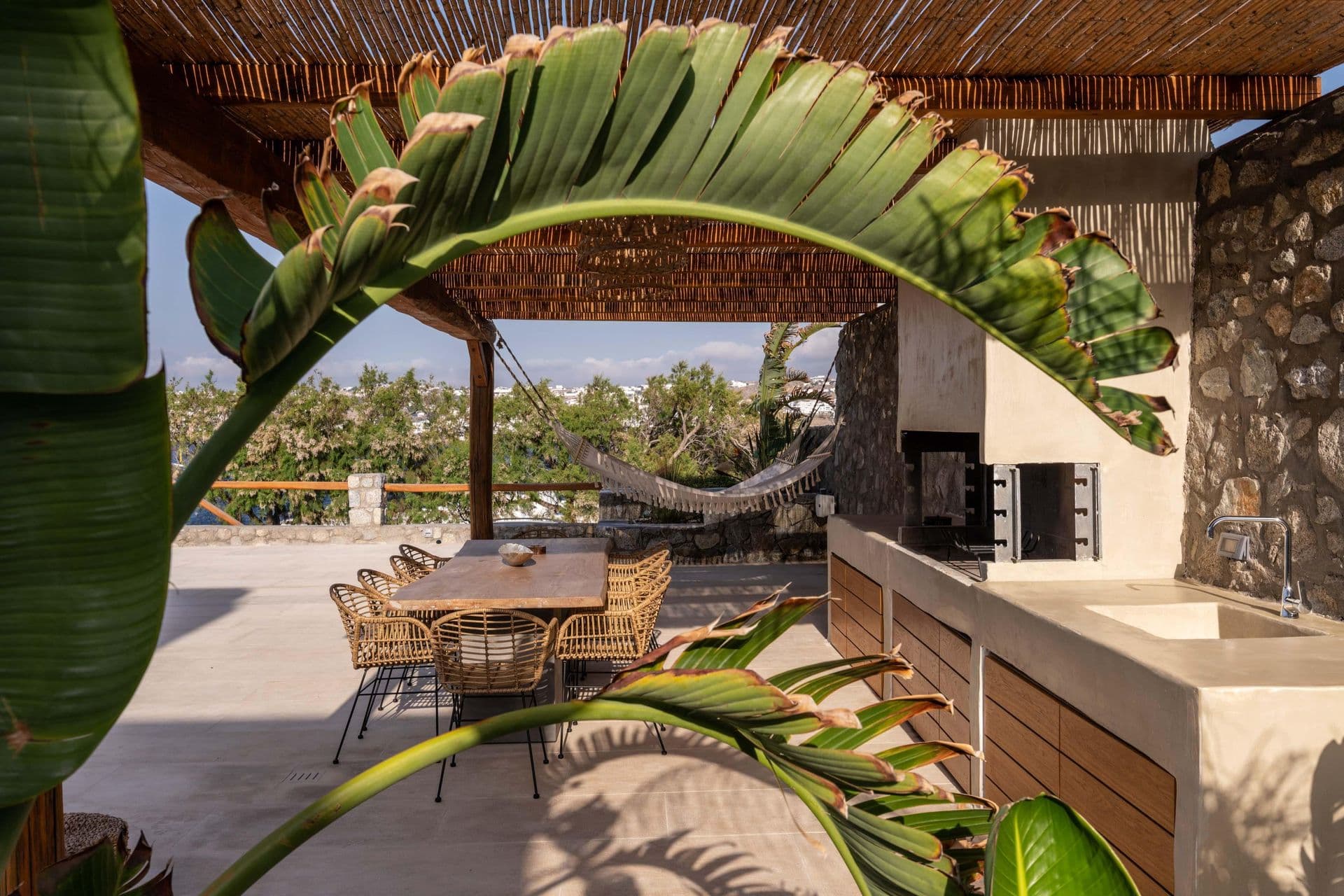 Shaded outdoor kitchen and barbecue area beneath a bamboo pergola