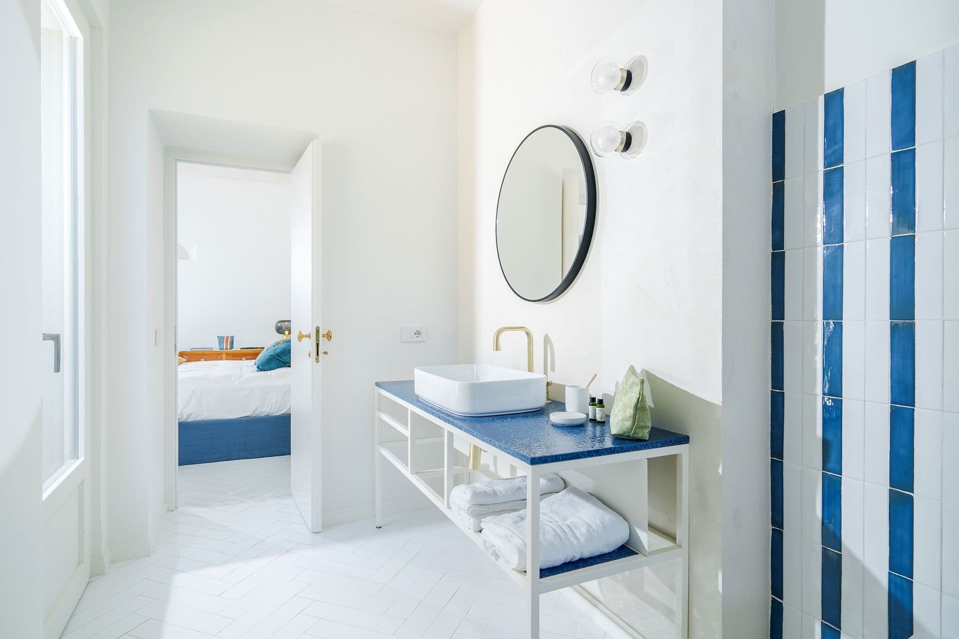 Bathroom with round mirror and navy vanity at Ocean House, Positano