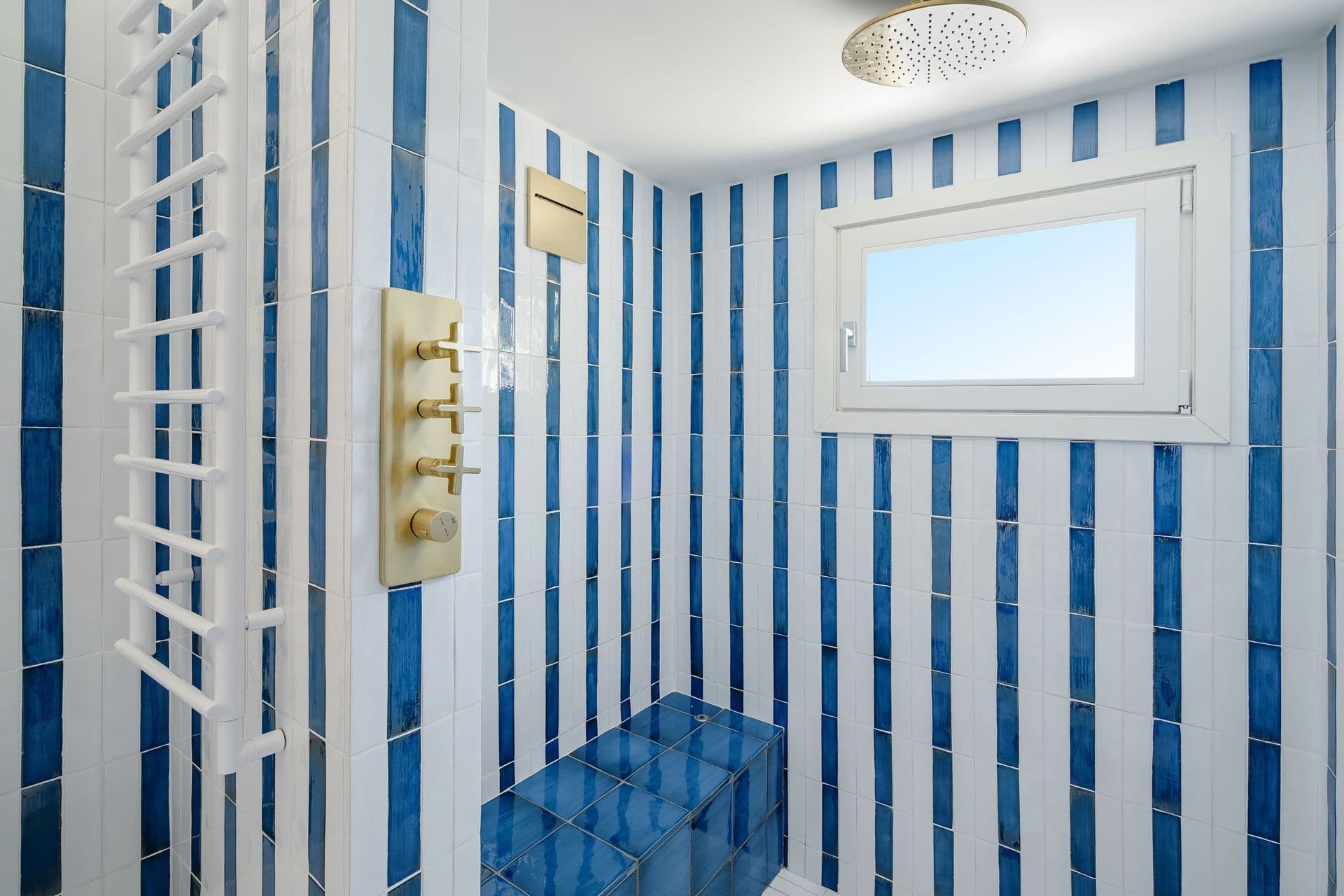 Bathroom with brass fittings and blue striped tiling at Ocean House, Positano