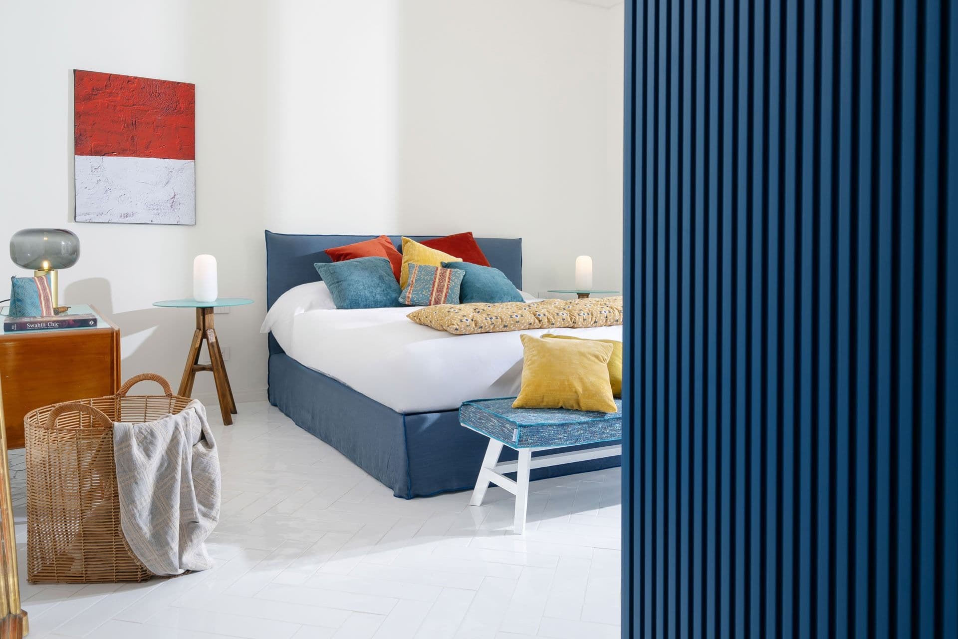 Bedroom with navy bed and bold red artwork at Ocean House, Positano