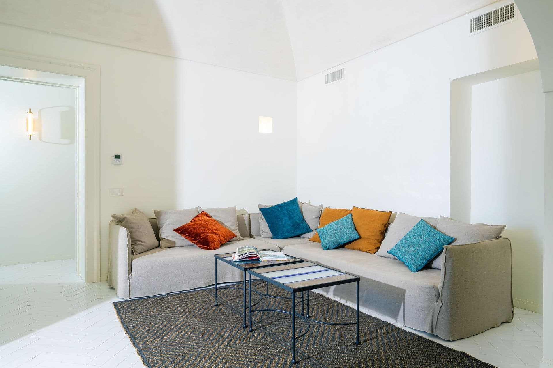 Bright living room with white sofa and colourful cushions at Ocean House, Positano