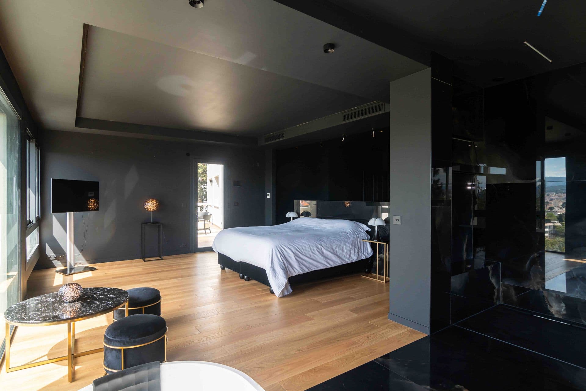 A bedroom with a black ceiling and full width windows framing distant hills