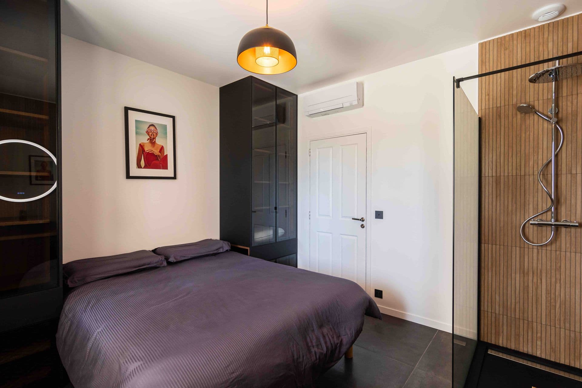 A dark toned bedroom with a plum bedspread and a walk in wardrobe