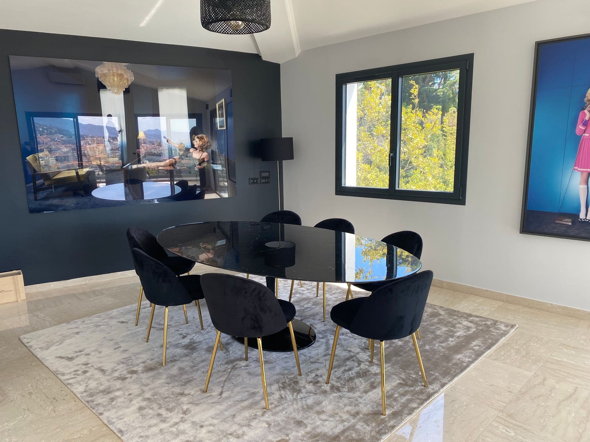 A dining table with black chairs set beside full height windows