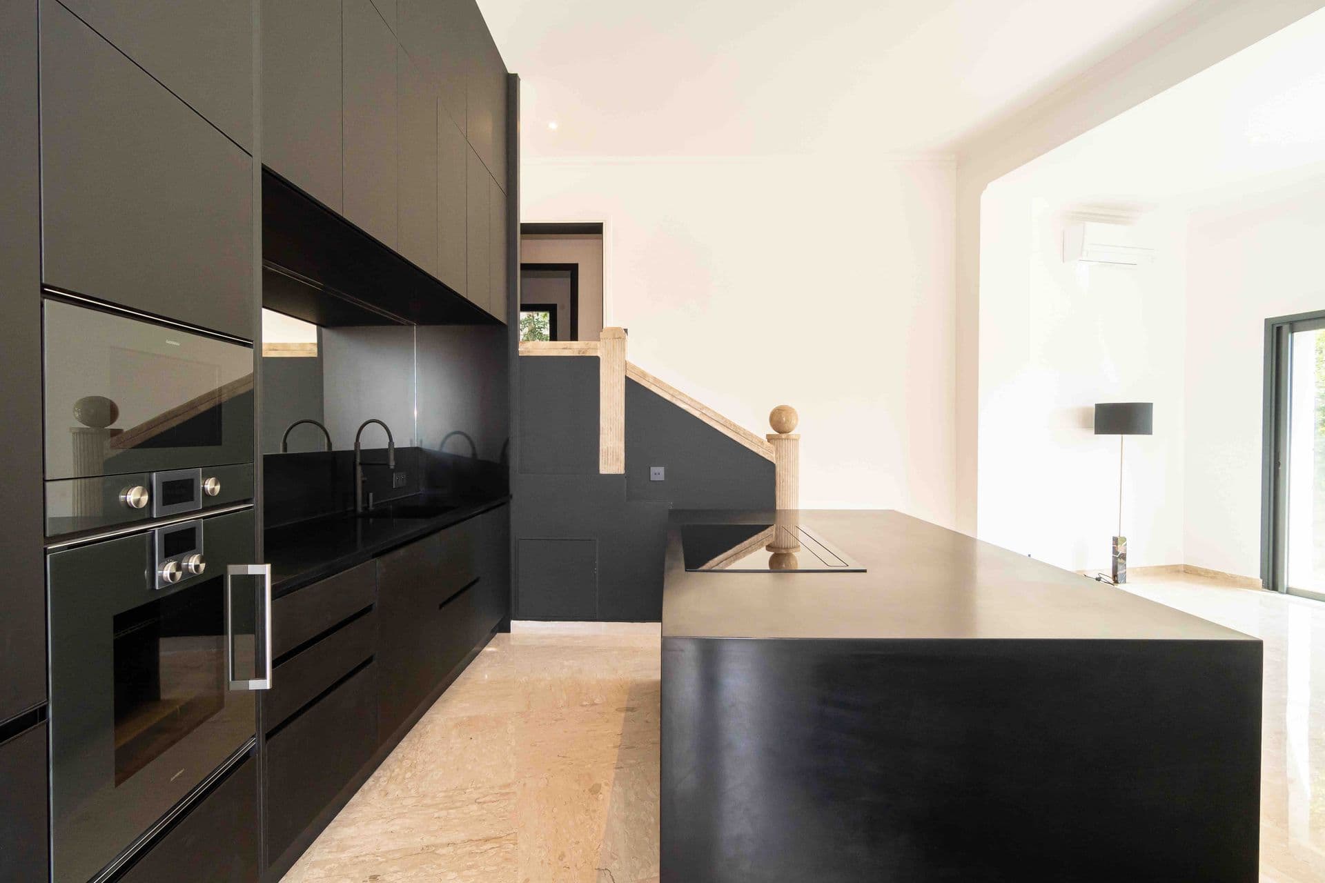 A sleek matte black kitchen with a large island and integrated appliances