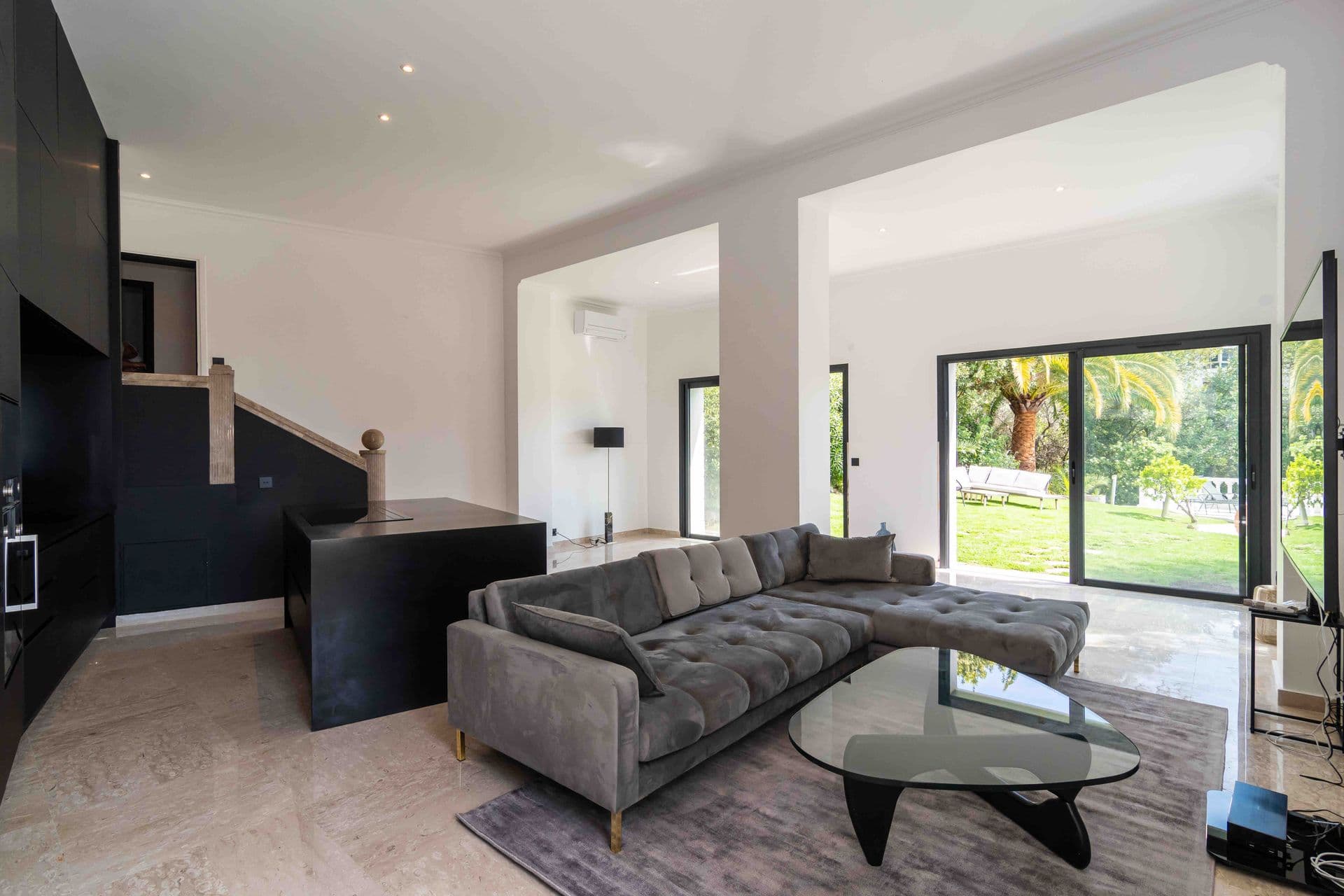 A light filled living room with a grey chaise sofa and glass coffee table