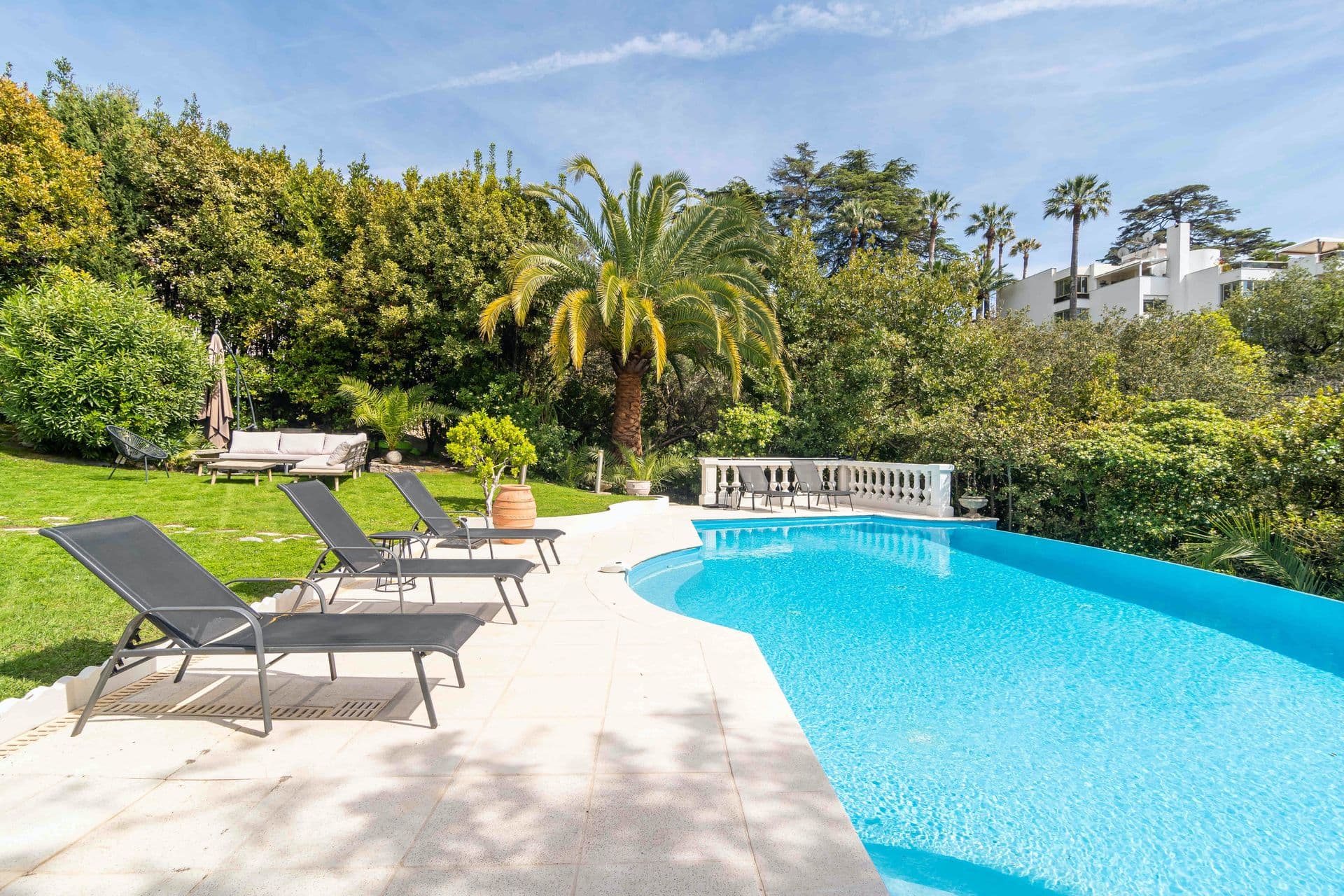 A landscaped swimming pool with sun loungers surrounded by mature palms