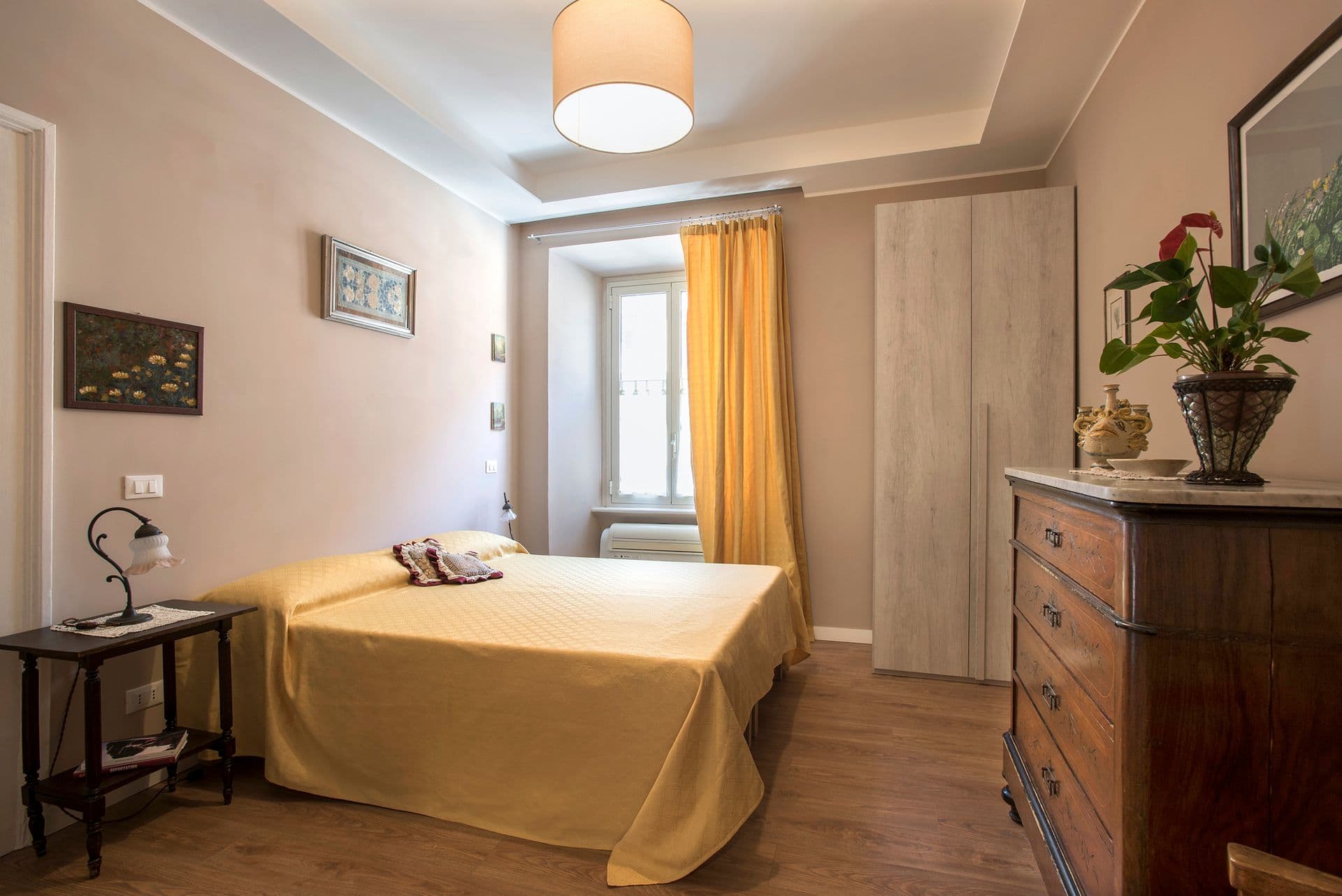 Guest bedroom with yellow bedspread and wooden chest of drawers