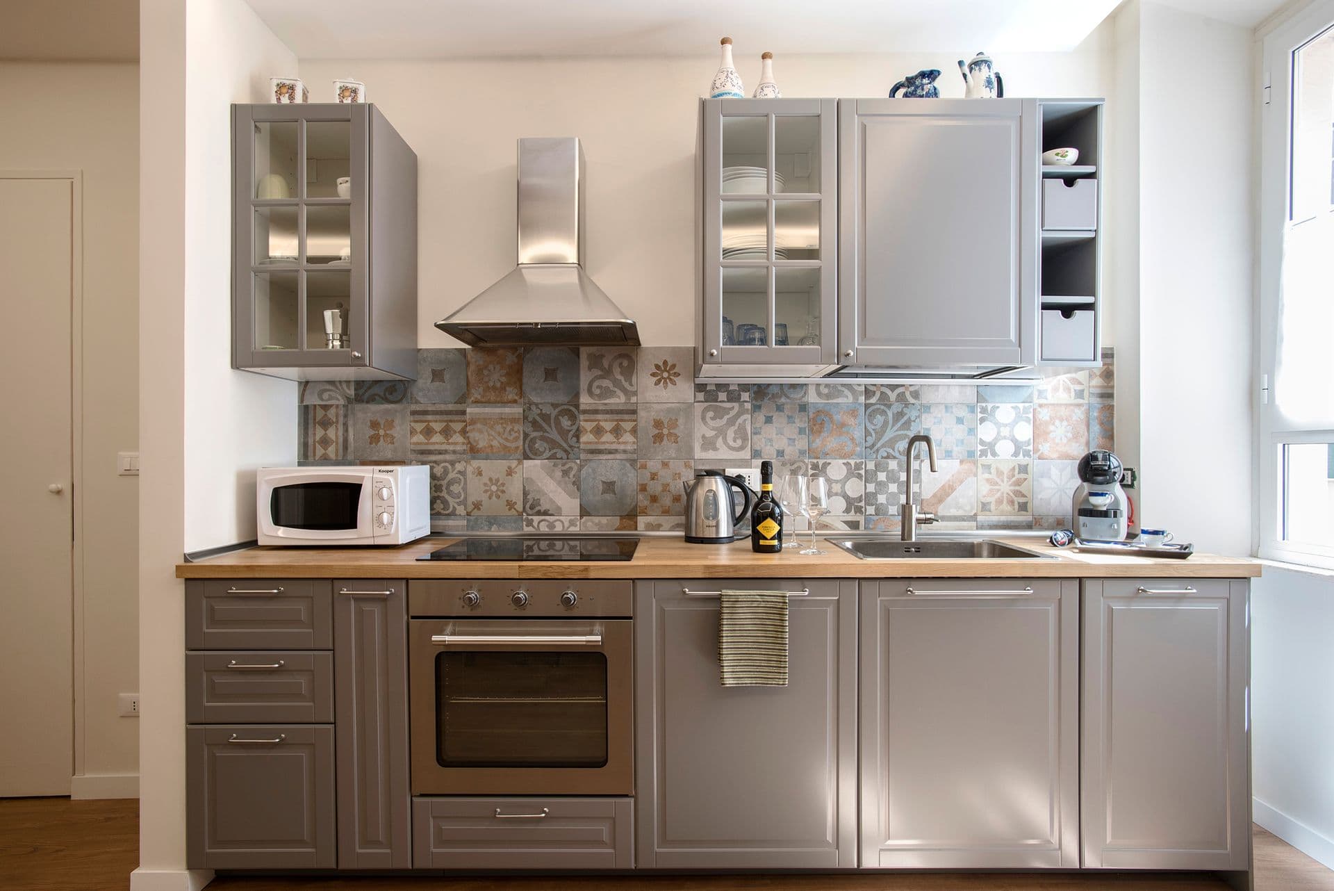 Fitted kitchen with stainless steel appliances and tiled splashback