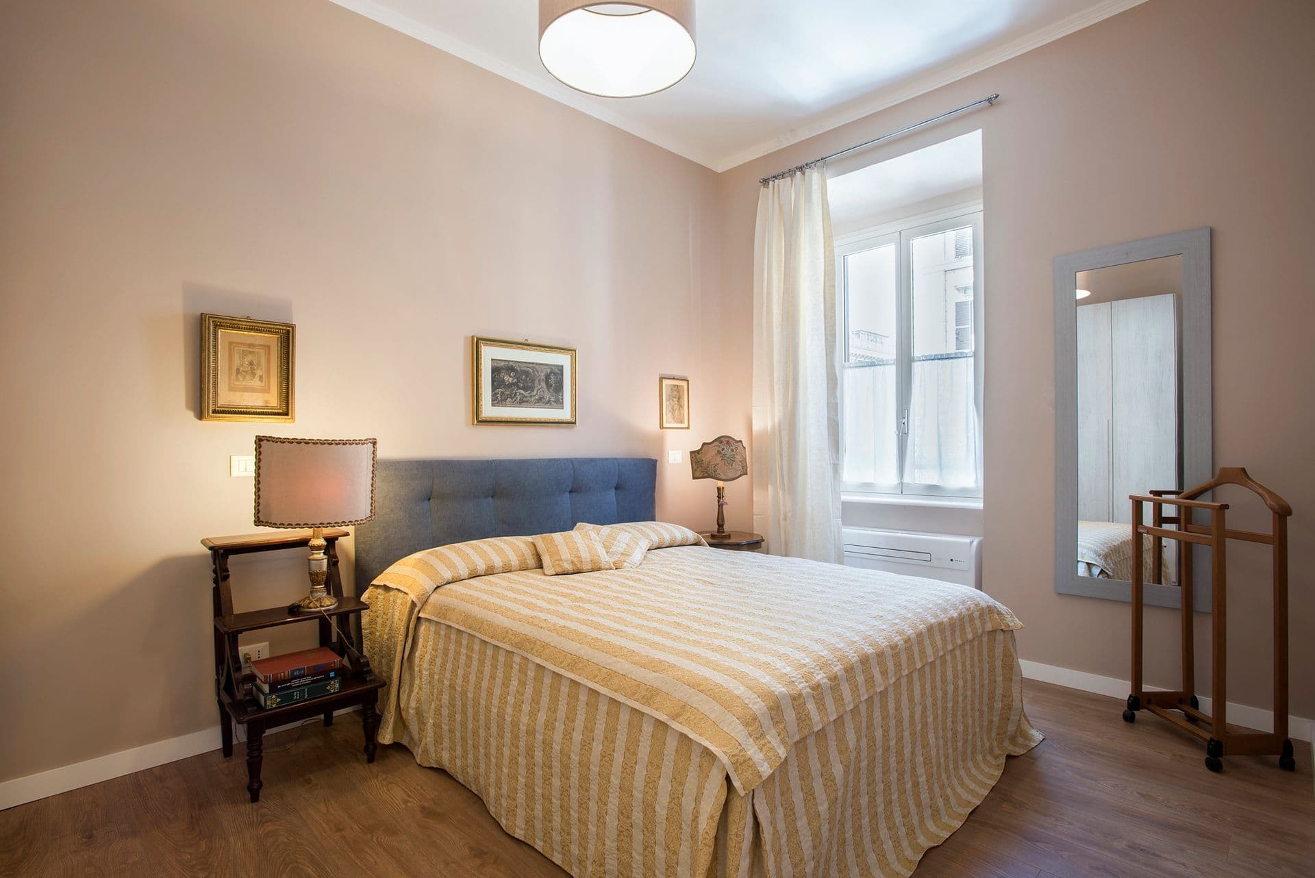 Second bedroom with upholstered headboard and full-length mirror